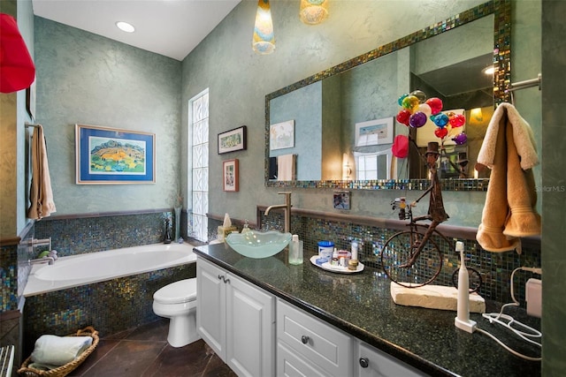 bathroom featuring toilet, vanity, tiled bath, and backsplash