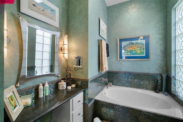 bathroom featuring vanity and tiled tub