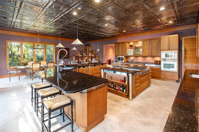 kitchen with decorative light fixtures, built in microwave, sink, oven, and a spacious island