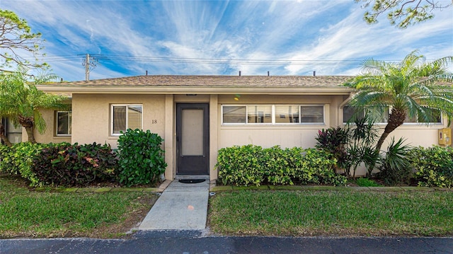 ranch-style home featuring stucco siding and a front yard