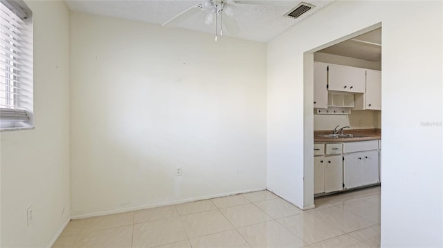 kitchen with white cabinetry, sink, light tile patterned floors, and ceiling fan