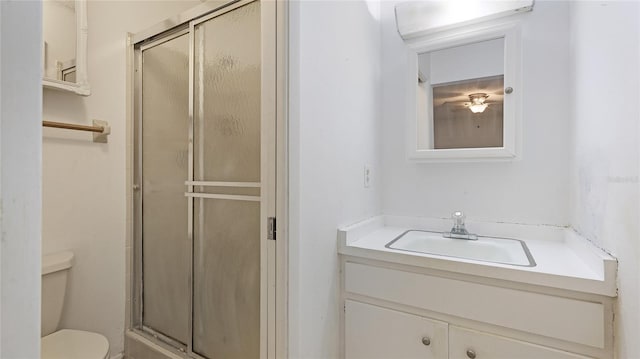 bathroom featuring vanity, a shower with shower door, and toilet