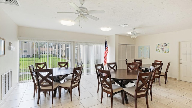 dining area with ceiling fan, light tile patterned floors, and a textured ceiling