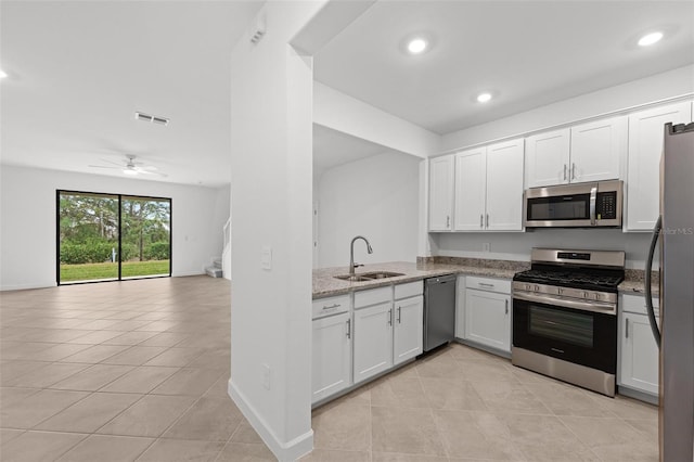 kitchen featuring sink, light tile patterned floors, appliances with stainless steel finishes, white cabinetry, and light stone counters