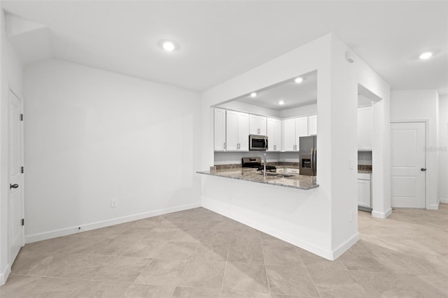 kitchen with appliances with stainless steel finishes, sink, white cabinets, kitchen peninsula, and light stone countertops