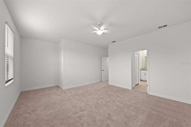 unfurnished bedroom with light colored carpet, ceiling fan, and ensuite bathroom