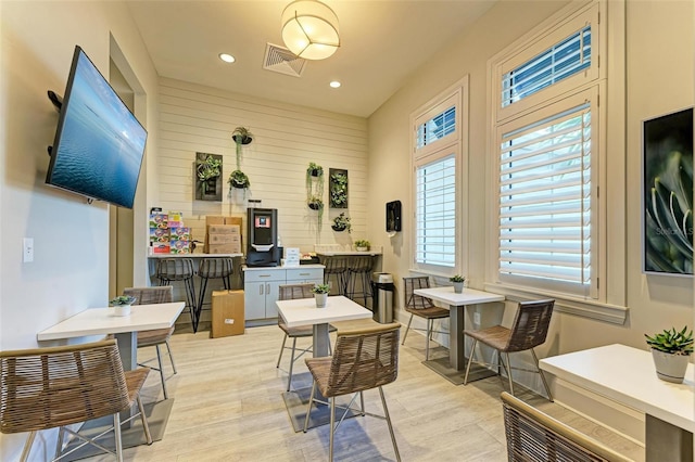 dining area featuring wooden walls and light wood-type flooring