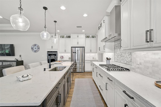 kitchen featuring white cabinetry, appliances with stainless steel finishes, a large island, and wall chimney range hood