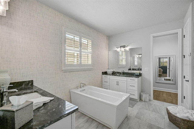 bathroom featuring vanity, a washtub, and a textured ceiling