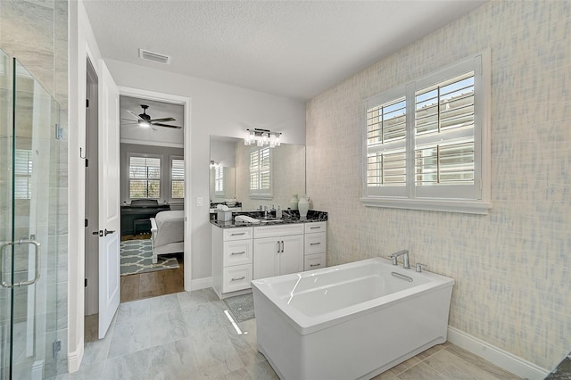 bathroom with ceiling fan, vanity, plus walk in shower, and a textured ceiling