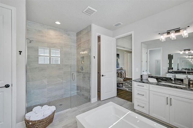 bathroom featuring vanity, shower with separate bathtub, and a textured ceiling