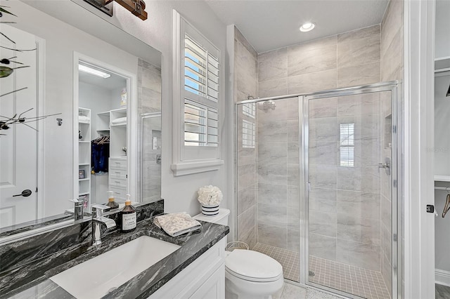 bathroom with an enclosed shower, vanity, and toilet