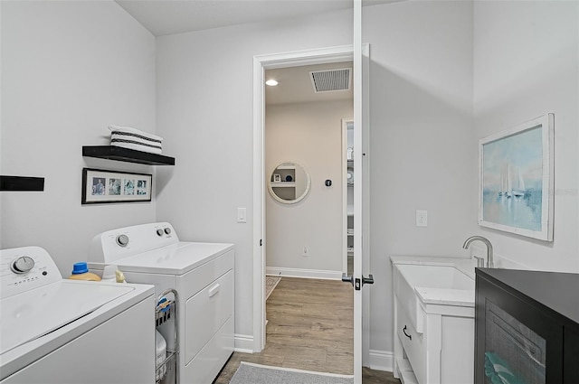 laundry room with sink, washer and clothes dryer, cabinets, and light wood-type flooring