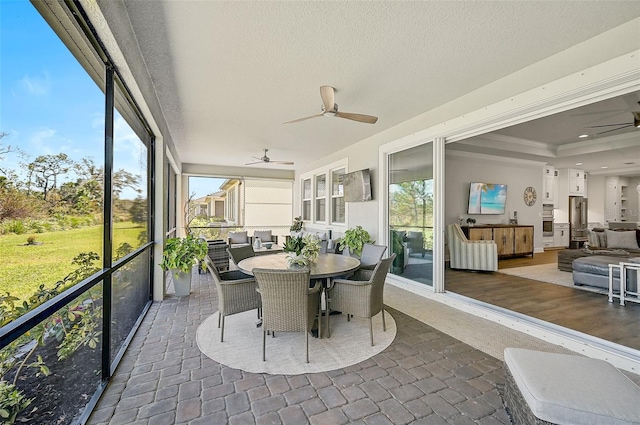 sunroom / solarium featuring a raised ceiling and ceiling fan