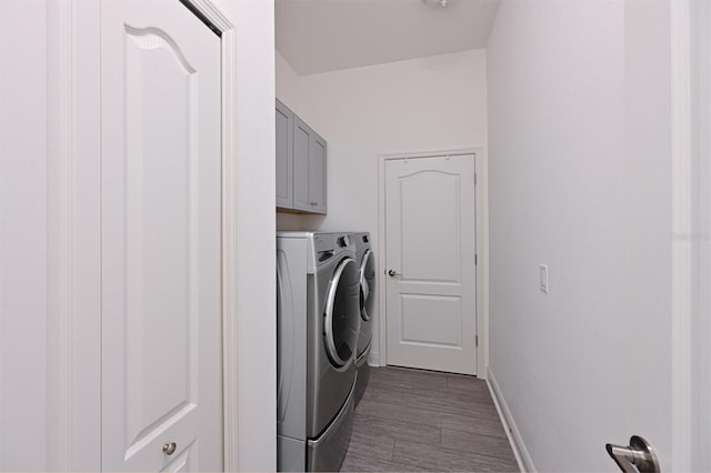 clothes washing area with cabinets, washing machine and dryer, and dark hardwood / wood-style flooring