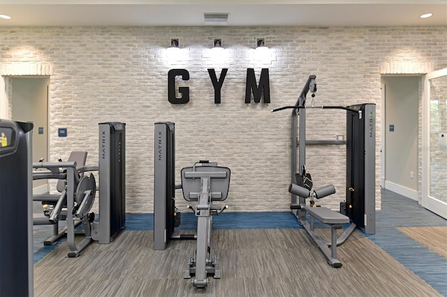 workout room featuring brick wall and dark hardwood / wood-style floors