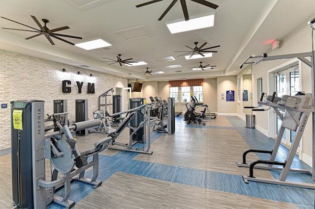 exercise room featuring brick wall and a tray ceiling