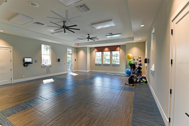 exercise area featuring ceiling fan and a tray ceiling