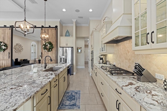 kitchen featuring sink, custom exhaust hood, cream cabinets, and hanging light fixtures