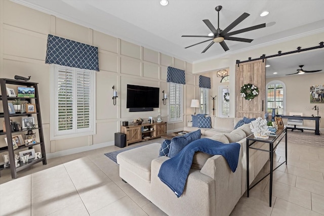 tiled living room with crown molding, ceiling fan, and a barn door