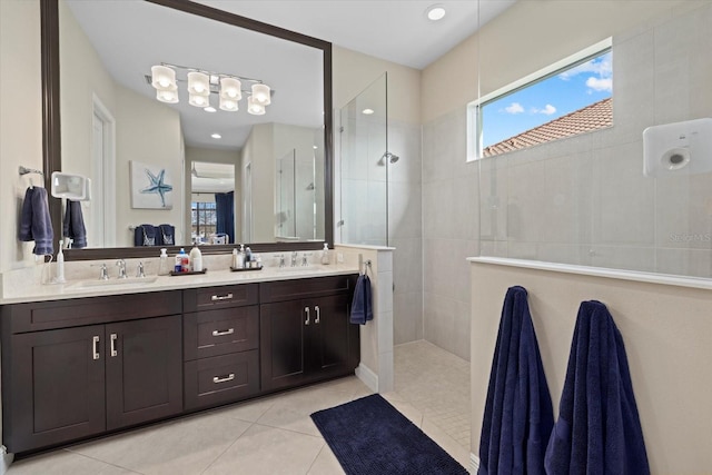 bathroom with a tile shower, vanity, and tile patterned floors