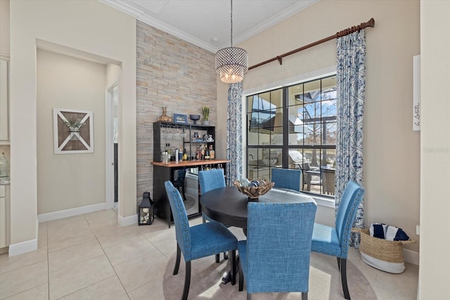 dining space with light tile patterned floors, ornamental molding, an inviting chandelier, and baseboards