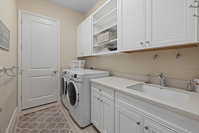 washroom featuring light tile patterned flooring, washing machine and dryer, a sink, baseboards, and cabinet space