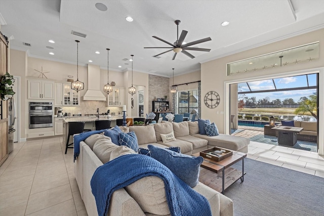 living area featuring light tile patterned floors, ceiling fan, visible vents, and crown molding