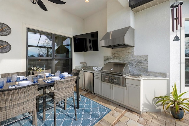 kitchen with gray cabinets, backsplash, ceiling fan, wall chimney range hood, and fridge