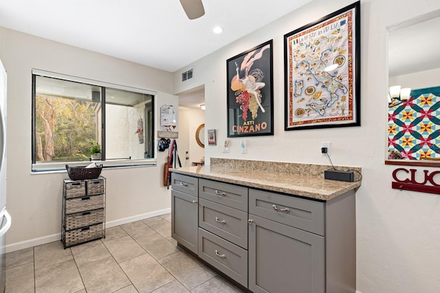 interior space featuring gray cabinets, light stone countertops, ceiling fan, and light tile patterned flooring