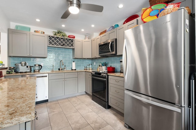 kitchen with appliances with stainless steel finishes, gray cabinetry, and light stone counters