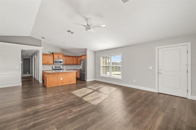 kitchen with stainless steel appliances, tasteful backsplash, a kitchen island, dark hardwood / wood-style flooring, and vaulted ceiling