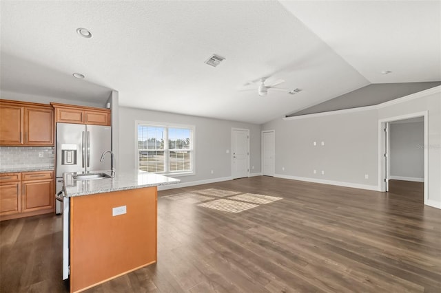 kitchen featuring sink, vaulted ceiling, a center island with sink, dark hardwood / wood-style flooring, and light stone countertops