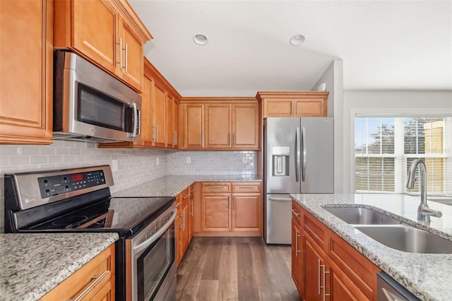 kitchen featuring dark hardwood / wood-style floors, tasteful backsplash, sink, light stone counters, and stainless steel appliances