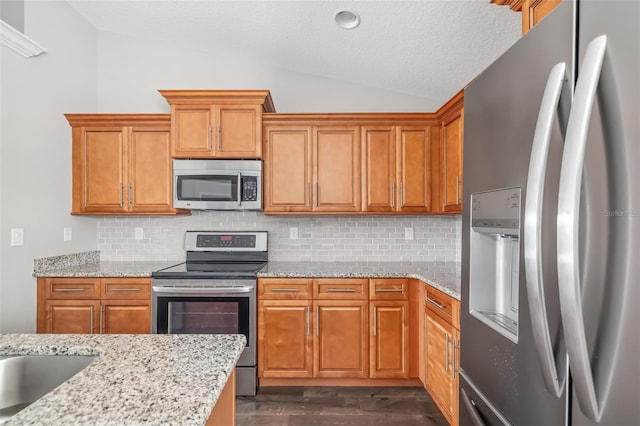 kitchen with stainless steel appliances, lofted ceiling, backsplash, and dark hardwood / wood-style flooring