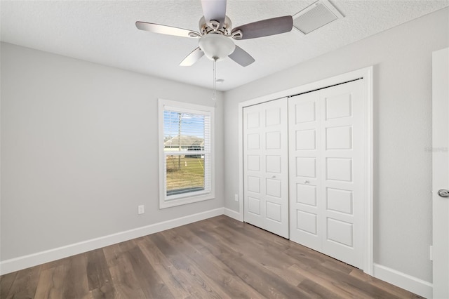 unfurnished bedroom with dark hardwood / wood-style flooring, ceiling fan, a closet, and a textured ceiling