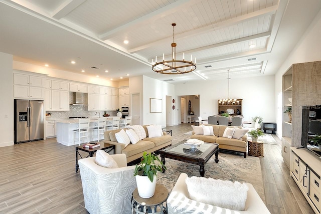 living room featuring beam ceiling, a chandelier, and sink