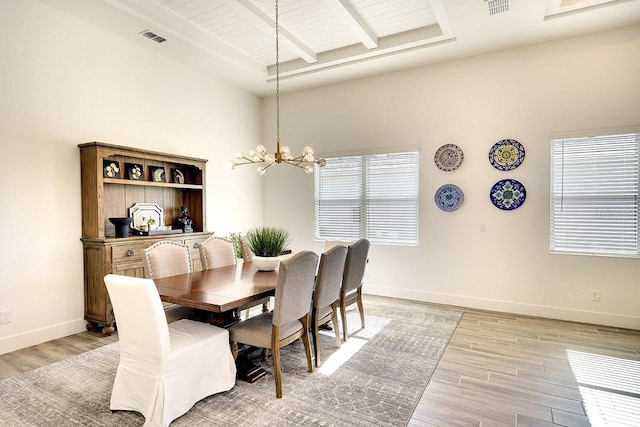 dining space with beamed ceiling, an inviting chandelier, and light hardwood / wood-style floors