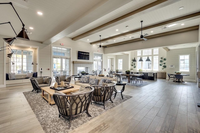 living room with beamed ceiling, ceiling fan, and light wood-type flooring