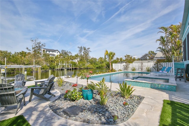 view of pool with a patio area, a water view, and an in ground hot tub