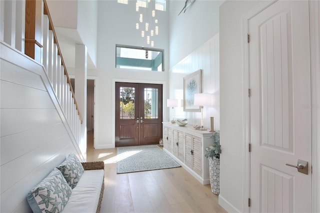 entrance foyer with light hardwood / wood-style flooring, french doors, and a high ceiling