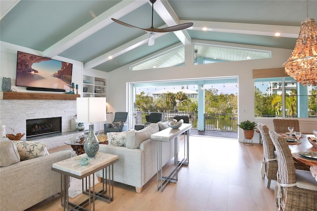 living room featuring ceiling fan, a fireplace, light hardwood / wood-style flooring, and vaulted ceiling with beams