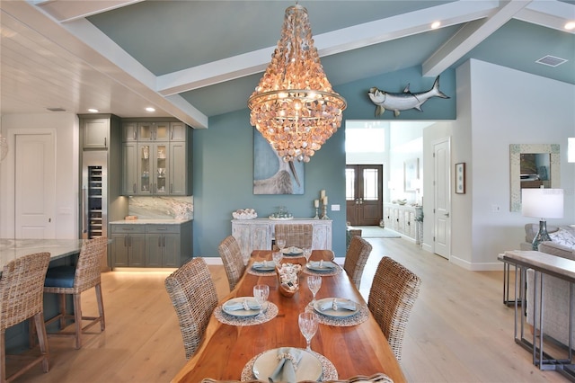 dining space featuring a notable chandelier, lofted ceiling with beams, and light hardwood / wood-style floors