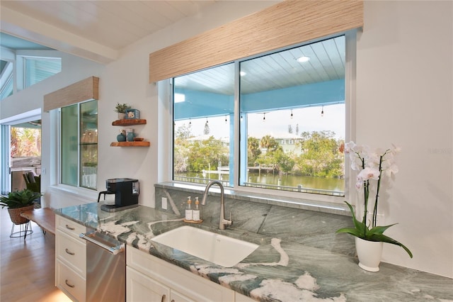 kitchen featuring sink, a water view, stone counters, hardwood / wood-style floors, and white cabinets