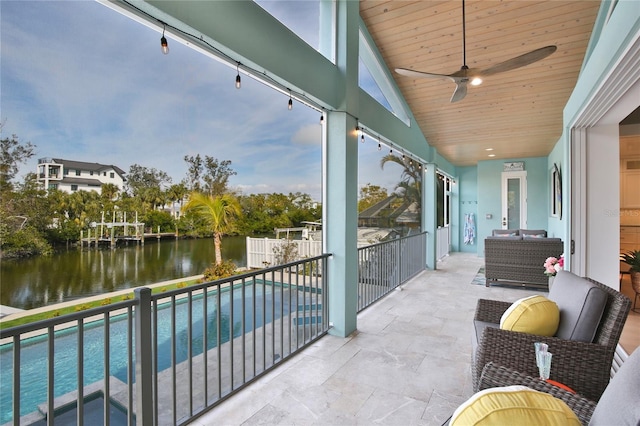 balcony featuring a water view, ceiling fan, an outdoor living space, and a patio area