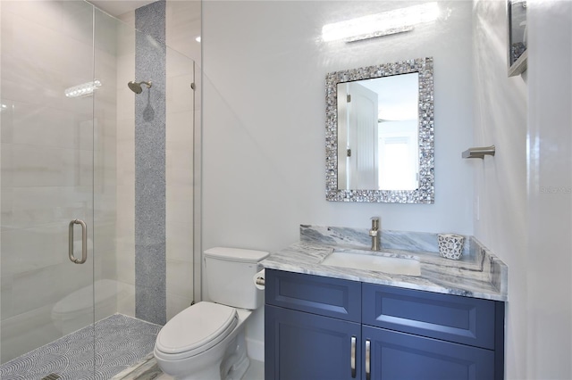 bathroom with vanity, a shower with door, and toilet