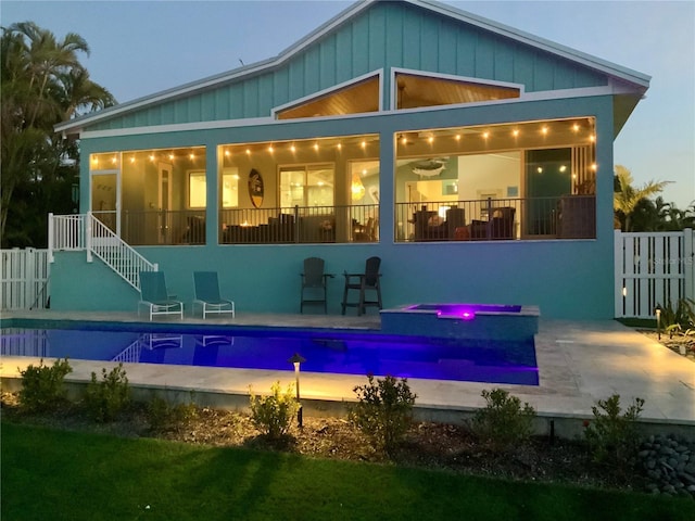 back house at dusk with a pool with hot tub and a patio