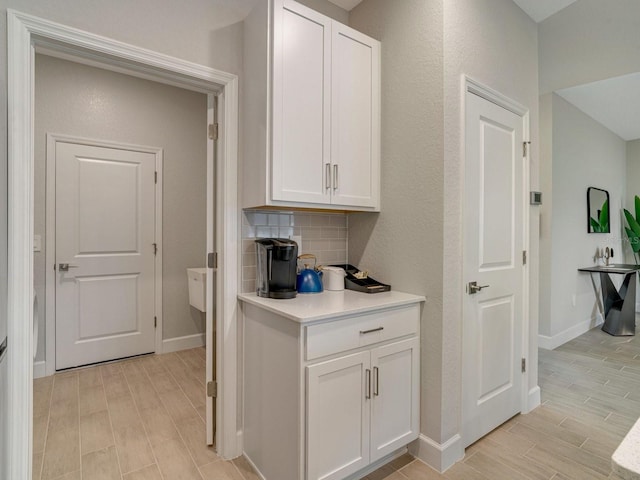 interior space with backsplash, light hardwood / wood-style flooring, and white cabinets