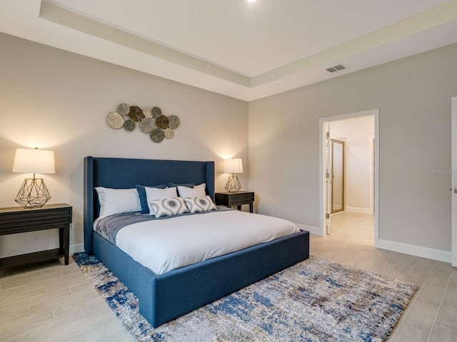 bedroom with ensuite bathroom and a raised ceiling