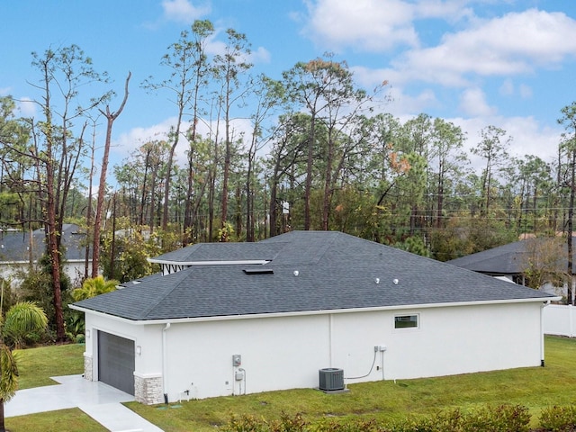 view of home's exterior with a garage, central AC unit, and a lawn